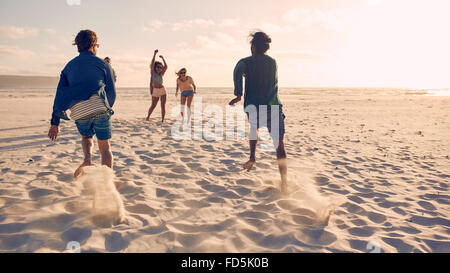 Gruppe von Jugendlichen ausgeführt und im Wettbewerb zusammen an einem Sandstrand. Junge Männer, die ein Rennen am Strand. Stockfoto