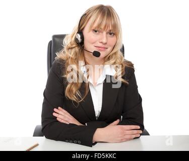 Freundliche junge call Center-Betreiber oder Rezeption tragen einen Kopfhörer sitzt an ihrem Schreibtisch mit verschränkten Armen in die Kamera Lächeln Stockfoto