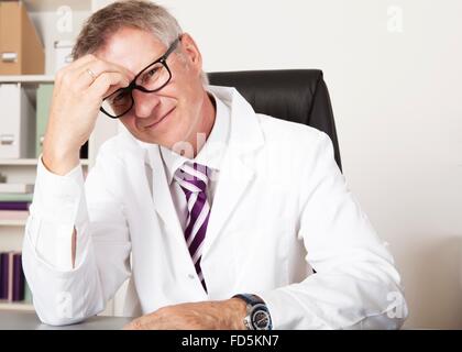 Arzt haben Kopfschmerzen, Blick in die Kamera zu sitzen Stockfoto
