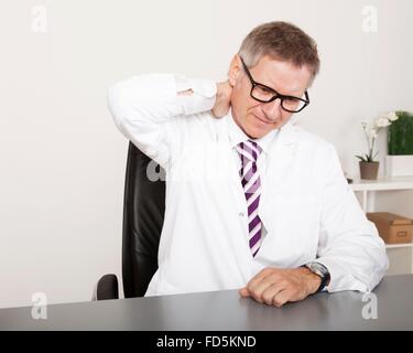 Erschöpften Arzt hält wieder Hals wegen Stress oder Schmerz Stockfoto