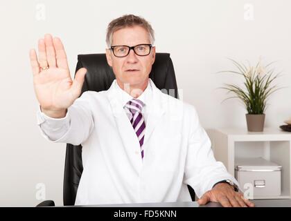 Ernst Arzt zeigen Hand-Stop-Schild auf Stuhl sitzend Stockfoto