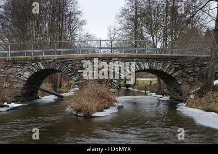 alten Stonebridge über das kalte Wasser an einem grauen Wintertag das Eis hinter dem Fluss Stockfoto