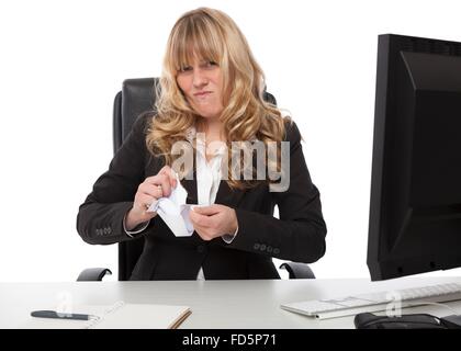 Angewidert Geschäftsfrau sitzt an ihrem Schreibtisch zerreißen ein Papierdokument mit schmerzverzerrtem Gesicht zeigt ihre Unzufriedenheit Stockfoto