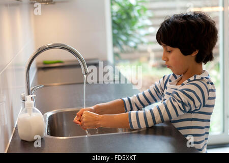 Acht Jahre alter Junge Händewaschen in der Küche Stockfoto