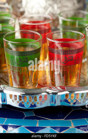 Marokkanischer Tee Gläser in den Farben der marokkanischen Fahne mit in arabischer Schrift geschrieben Tee Stockfoto