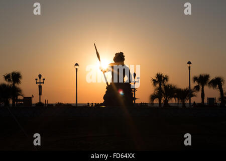 Silhouette von King Neptune Statue mit Sonnenaufgang über dem Strand hinter ihm. Stockfoto