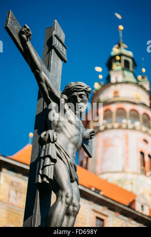 Die Statue des gekreuzigten Christus am Kreuz auf Lazebnicky die meisten Brücke im Hintergrund der alte Schlossturm in Cesky Krumlov, Tschechische Stockfoto