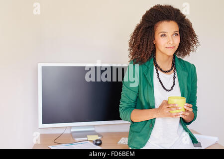 Lateinamerikanische Geschäftsfrau sucht nachdenklich mit einer Tasse von co Stockfoto