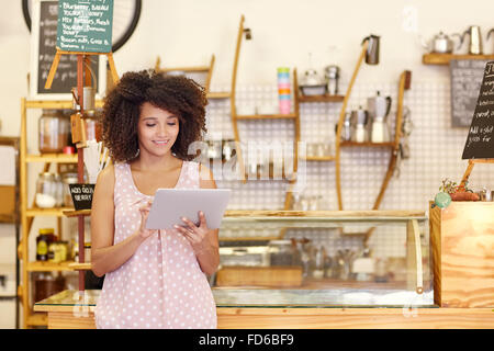 Inhaber eines kleinen Unternehmens mit einem Tablet in ihrem Café Stockfoto