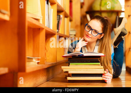 Highschool Bildungskonzept. Studentin, charmante lange Haare Mädchen Blau Brille arbeiten in College-Bibliothek mit Stapel Bücher. Stockfoto