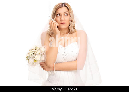 Nervöse Braut im weißen Hochzeitskleid halten einen Blumenstrauß und rauchte eine Zigarette, die isoliert auf weißem Hintergrund Stockfoto