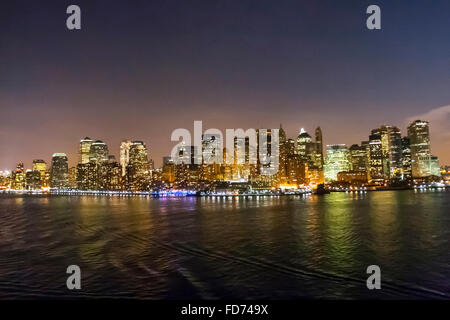 Das Manhattan Financial District gesehen aus dem Hafen von New York in der Nacht in New York City, USA. Stockfoto