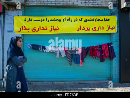Frau vorbei an einer Wand der Güte geschaffen, um Kleidung kostenlos an arme Menschen, Central County, Yazd, Iran Stockfoto