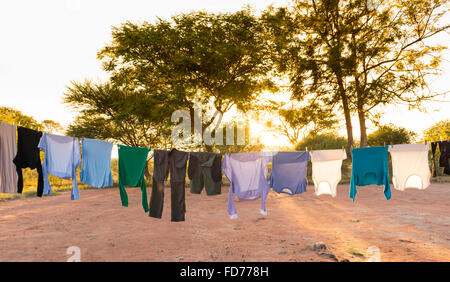 Herren und Damen Wäsche trocknen auf Outdoor-Wäscheleine mit Klammern und Sonne in Streaming-hinter Stockfoto