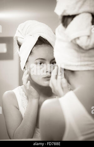 Anwenden von Frau Maske feuchtigkeitsspendende Hautcreme auf Gesicht in Badezimmerspiegel. Mädchen kümmert sich um ihren Teint Schichtung Maske Stockfoto