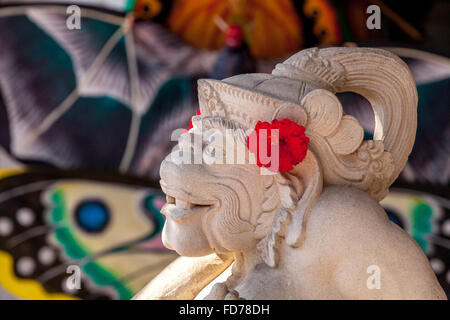 Affengott Hanuman aus Stein mit roten Hibiskus Blumen, weißer Kalkstein, Hanuman, Hinduismus geschnitzt, hinduistische,,, Straße Szene, Ubud, Stockfoto