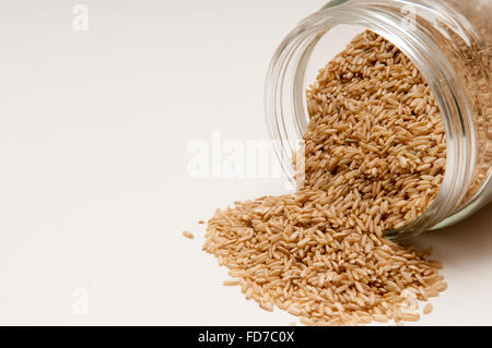 Brauner Reis gegossen aus dem Glas Stockfoto