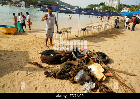 Männer sammeln Müll aus dem Meer am Playa Caleta Beach, Acapulco, Mexiko. Stockfoto