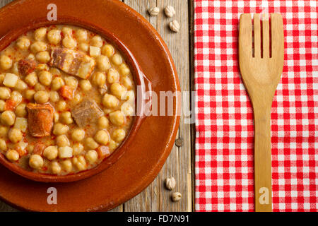 Spanischen Cocido in einen Tontopf und Gericht, getrocknete Kichererbsen und einer hölzernen Gabel Stockfoto