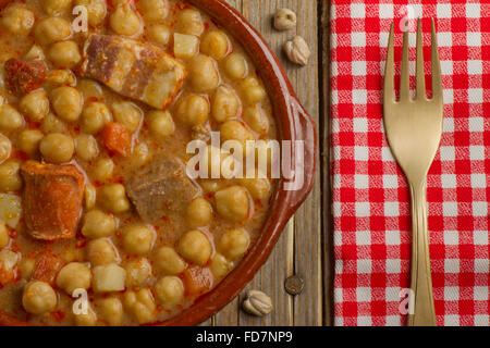 Spanischen Cocido in einem Tontopf, goldene Gabel und eine rot-weiße Serviette Stockfoto