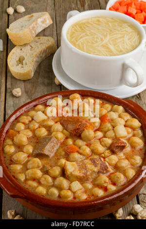 Spanischen Cocido, Suppe in eine Schüssel weiß, Brot und Karotten in einer Schüssel auf einem Holztisch Stockfoto