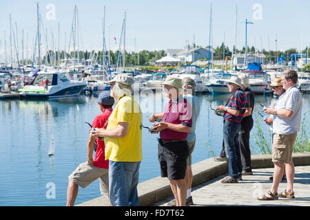 Gruppe von älteren Männern racing mit remote gesteuerten kleine Segelboote an einem hellen Sommertag in einer Marina. Stockfoto