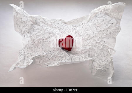 Ein rotes Herz in dem Hintergrund einer zerknitterten weiß Tissue-Papier, die mit "Cariad', das walisische Wort für"Liebe"eingeschrieben worden. Stockfoto