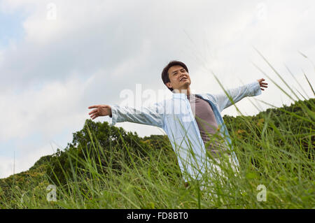 Chinesischer Mann ausstreckten Arme in der Natur Stockfoto