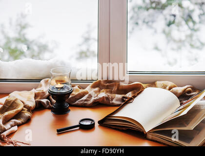 Öffnen, Fotoalbum, Kerze, Lupe und und Beige warmen Plaid befindet sich auf einer stilisierten hölzerne Fensterbank. Winter-Konzept von c Stockfoto