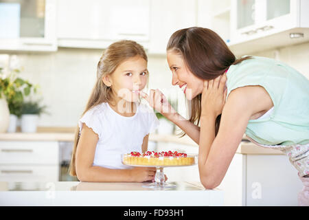 Mutter und Tochter Verkostung frischer Obstkuchen in der Küche Stockfoto