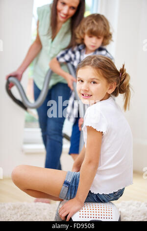 Mutter und Kinder gemeinsam mit Staubsauger zu Hause Stockfoto