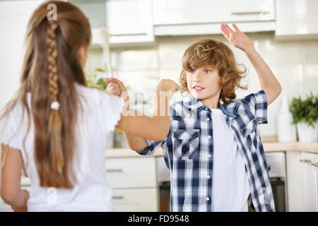 Kinder kämpfen mit Holzlöffel im Scherz in der Küche Stockfoto