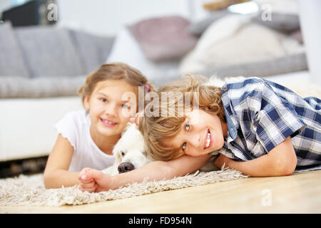Zwei glückliche Kinder, die spielen mit Golden Retriever Hund zu Hause Stockfoto