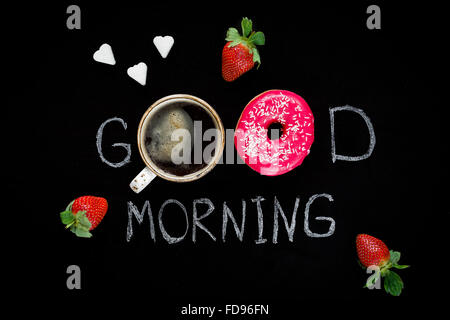 Donut, Tasse Kaffee und Herz geformten Stück Würfelzucker. Guten Morgen Gruß geschrieben am schwarzen Tafel. Ansicht von Tabelle oben. Frühstück Stockfoto