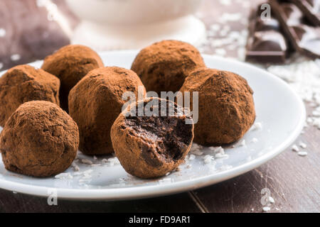 Hausgemachte gesunde vegane Schokolade Trüffel mit Terminen, Kokosflocken und Haferflocken auf weißem Teller serviert Stockfoto