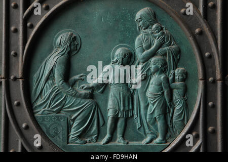 St. Ludmila Lehre St. Wenzel zu lesen. Bronzerelief tschechischen Künstlers Josef Mánes über dem Haupteingang der Kirche der Heiligen Cyrill und Methodius auf Karlinske Platz im Stadtteil Karlin in Prag, Tschechien. Drahomira Herzogin von Stodor, Mutter des Heiligen Wenzel, die die Ermordung zu St. Ludmila spät bestellt ist offensichtlich auf der rechten Seite dargestellt. Stockfoto