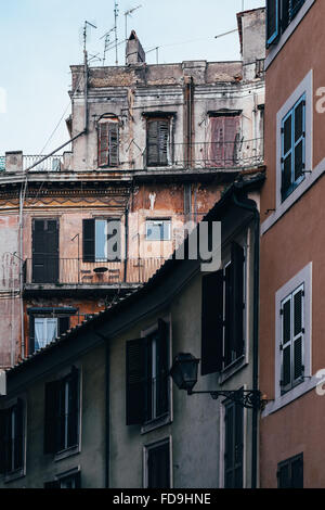 Geschichtete Gebäude mit Fensterläden Zeit getragen und grobe Stuckwänden in Rom, Italien. Stockfoto