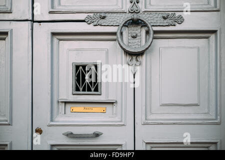 Ein Detail einer eleganten alten Tür in Rom, Italien, mit einem reich verzierten Klopfer, Briefkasten und ein kleines Fenster. Stockfoto