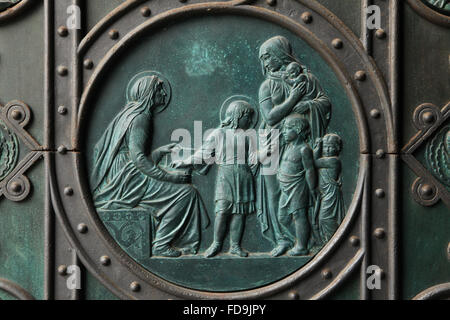 St. Ludmila Lehre St. Wenzel zu lesen. Bronzerelief tschechischen Künstlers Josef Mánes über dem Haupteingang der Kirche der Heiligen Cyrill und Methodius auf Karlinske Platz im Stadtteil Karlin in Prag, Tschechien. Drahomira Herzogin von Stodor, Mutter des Heiligen Wenzel, die die Ermordung zu St. Ludmila spät bestellt ist offensichtlich auf der rechten Seite dargestellt. Stockfoto