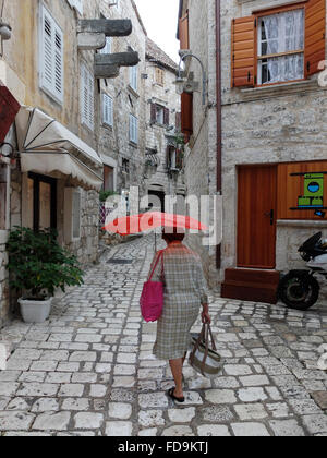 Hvar, Kroatien, geht Frau mit roten Regenschirm durch die Straßen Stockfoto