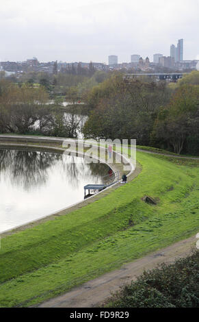 Ein Fischer steht neben dem Fluss Lee Nr. 2 Reservoir in Tottenham, Nord London, UK. London Skyline im Hintergrund. Stockfoto