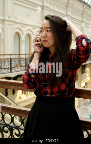 Mädchen am Telefon zu sprechen und ihr Haar im roten Hemd Stockfoto