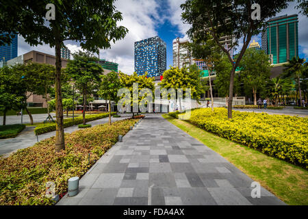 Gehweg an einem Park und Hochhäuser am Bonifacio Global City in Taguig, Metro Manila, Philippinen. Stockfoto