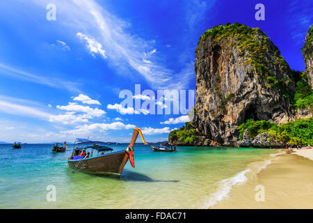 Thailand, Krabi. Longtail-Boot am tropischen Strand mit Kalkfelsen. Stockfoto