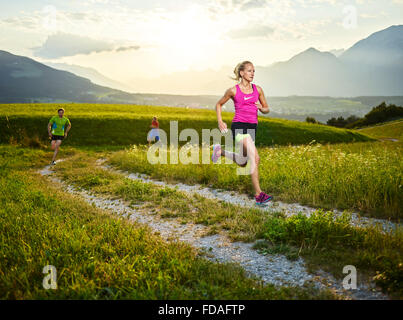 Junge Frau in ihren Zwanzigern, die auf Weg durch Felder, mehr Läufer, Rosengarten, Patsch, Tirol, Österreich Stockfoto