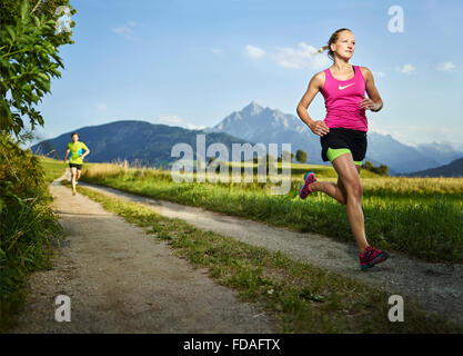 Junge Frau in ihren Zwanzigern, die auf Weg durch Felder, Rosengarten, Tirol, Österreich Stockfoto
