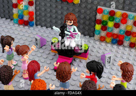 LEGO-Konzert mit dem Musiker und Publikum. LEGO-Freunde-Mädchen-Minifigur mit e-Gitarre auf der Bühne mit Mikrofon. Stockfoto