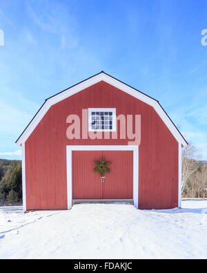 Frontansicht einer bunt bemalten rote traditionelle Neuengland Scheune im Winter von Schnee umgeben. Stockfoto