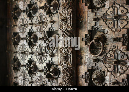 Full-Frame-Nahaufnahme von einer stark gravierte Holzschnitzerei Holz Haustüren mit kreisförmigen Türgriffe zieht in Indien Stockfoto