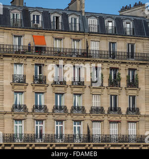 eine einzelne orange Markise links aufgerollt werden, am Ende des Tages auf einer Wohnung Block Fassade von Fenstern und Balkonen, klarer blauen Himmel, Paris Stockfoto